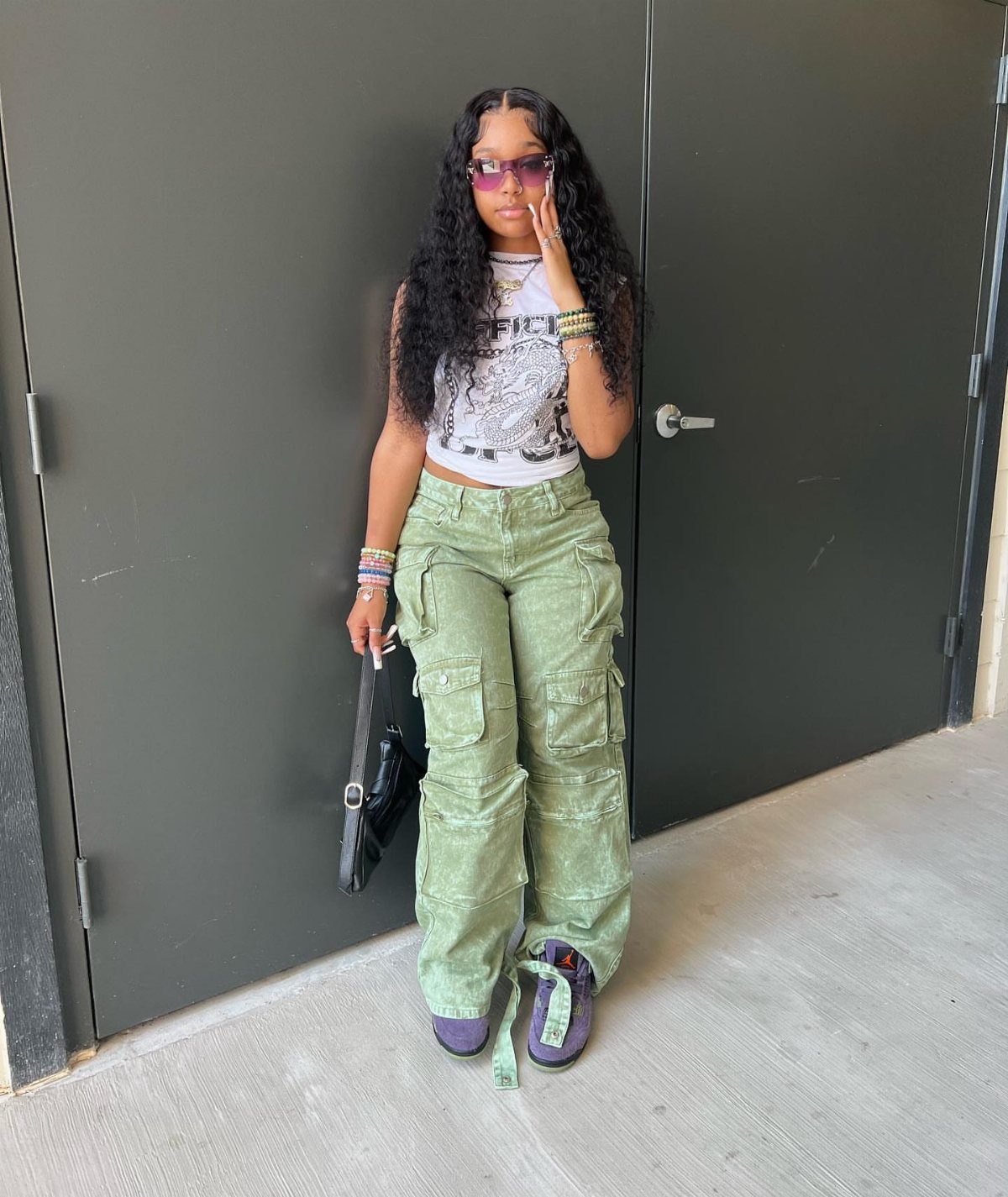Woman wearing a white graphic tee, green cargo pants, and purple sneakers.