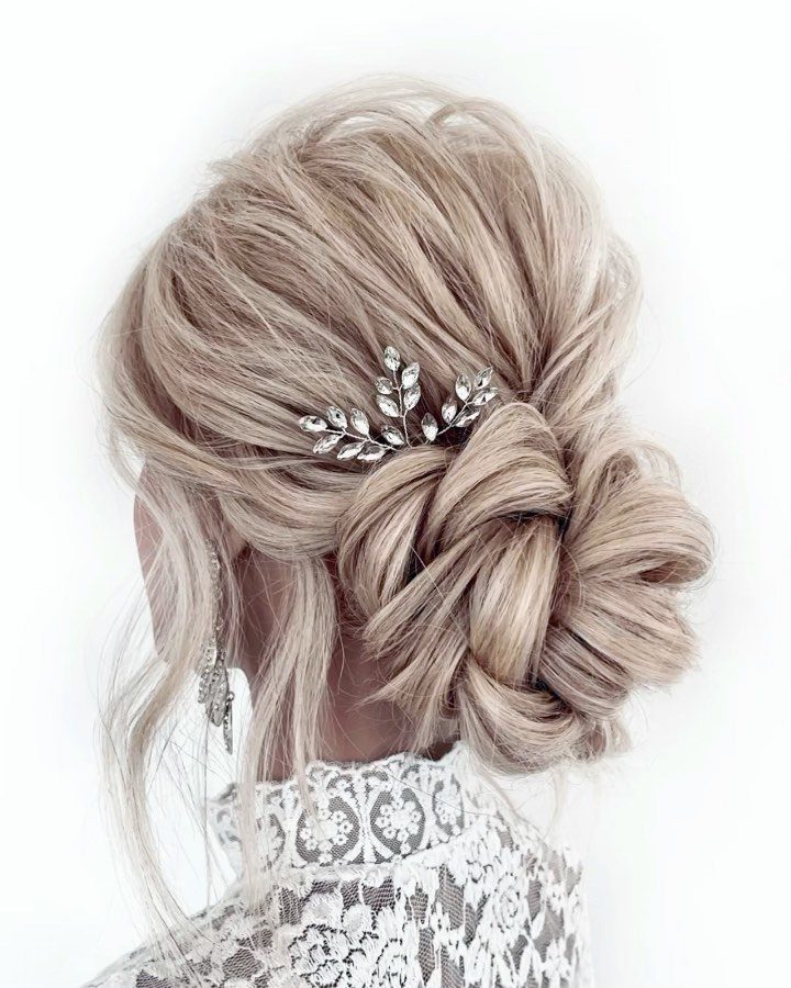Blonde hair styled in a textured low bun with a silver leaf hairpiece.
